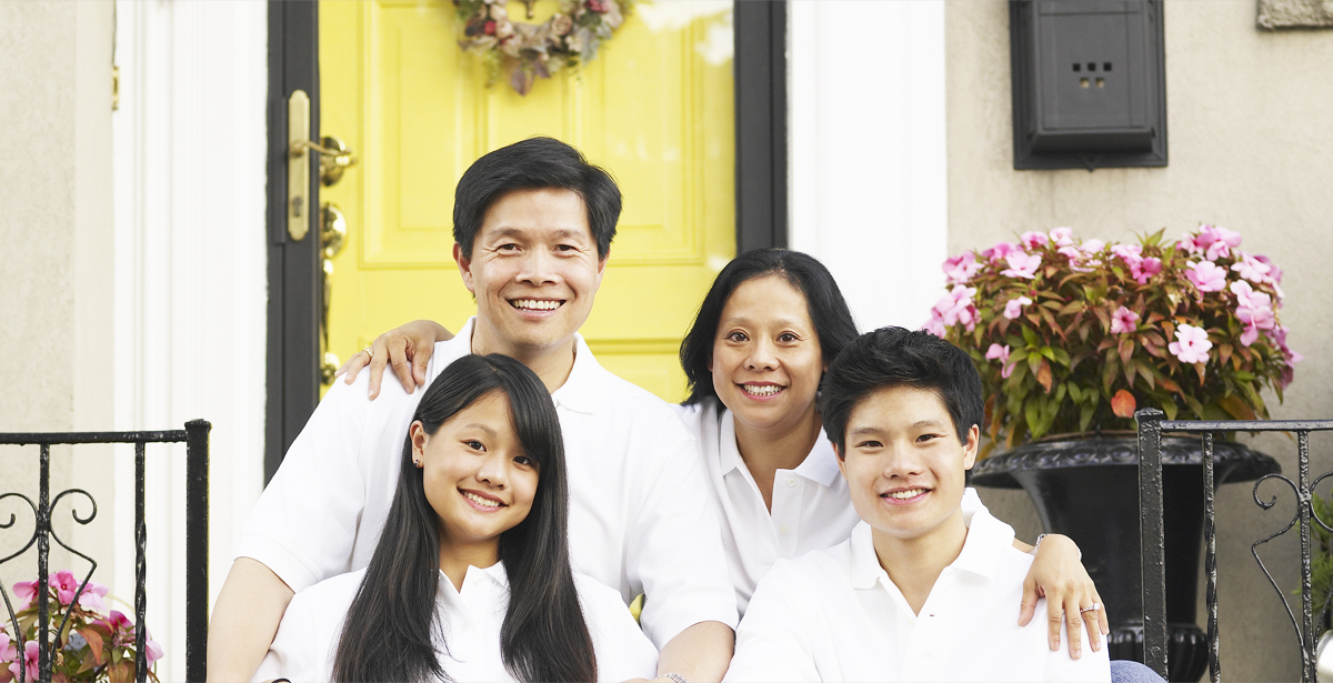 Family of four smiling on front steps